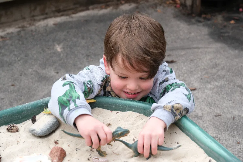 child playing with toys in sandpit